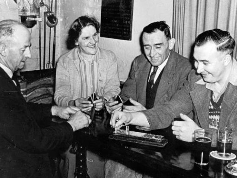 c1960, landlady Isabella Arnott plays crib with three of her cus. (Pub, Publican, Customers). Published on 30-09-2020 